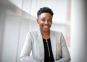 Solution - Industrial Heating & Drying 35 Confident African American businesswoman smiling inside a modern office space.